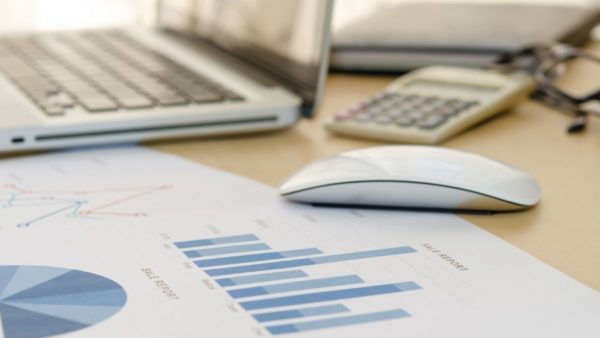 accounting documents sitting on a desk with a computer and mouse